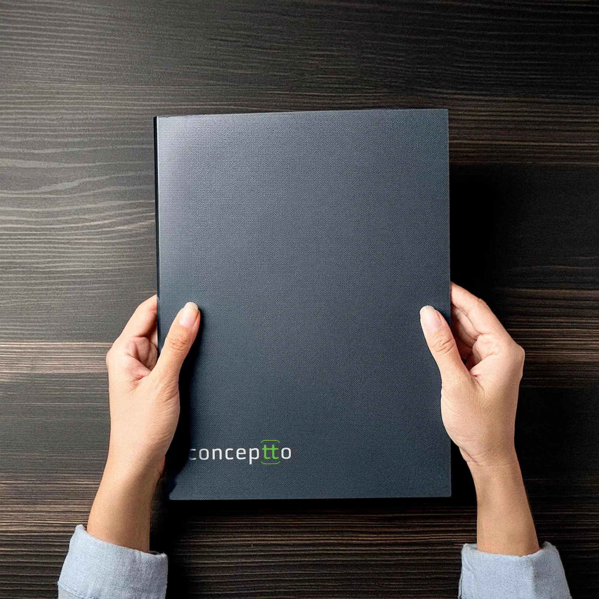 Carpeta corporativa de Conceptto sostenida sobre una mesa de madera